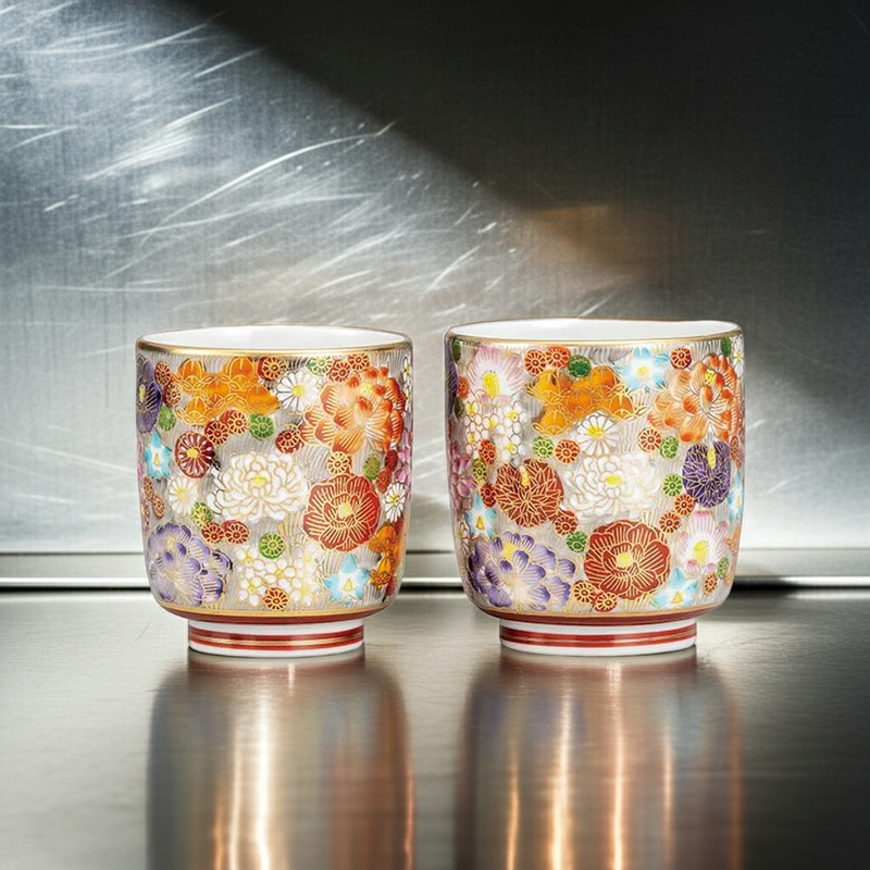 Two colorful ceramic cups with floral patterns on a metallic surface.